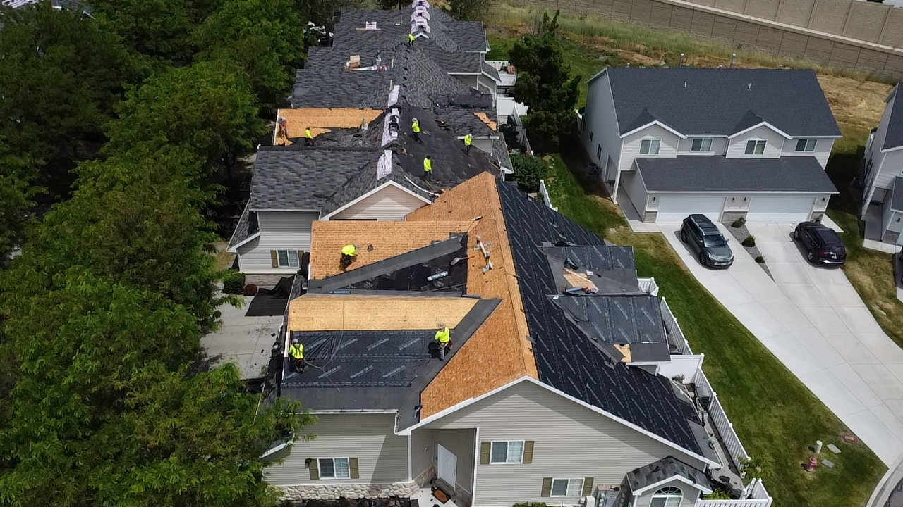 Roofing crew tearing off and re-decking a row of Salt Lake City homes